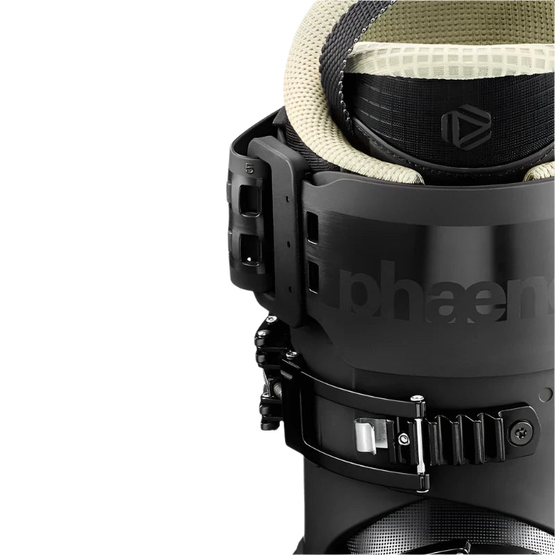 An up close view of the top of a ski boot. The power strap is black and a beige colored liner peeks out the top.