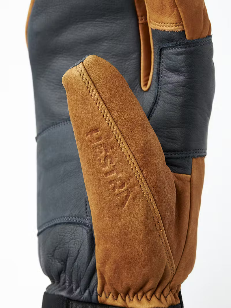 Close-up of a brown leather glove with 'Hestra' branding on a white background