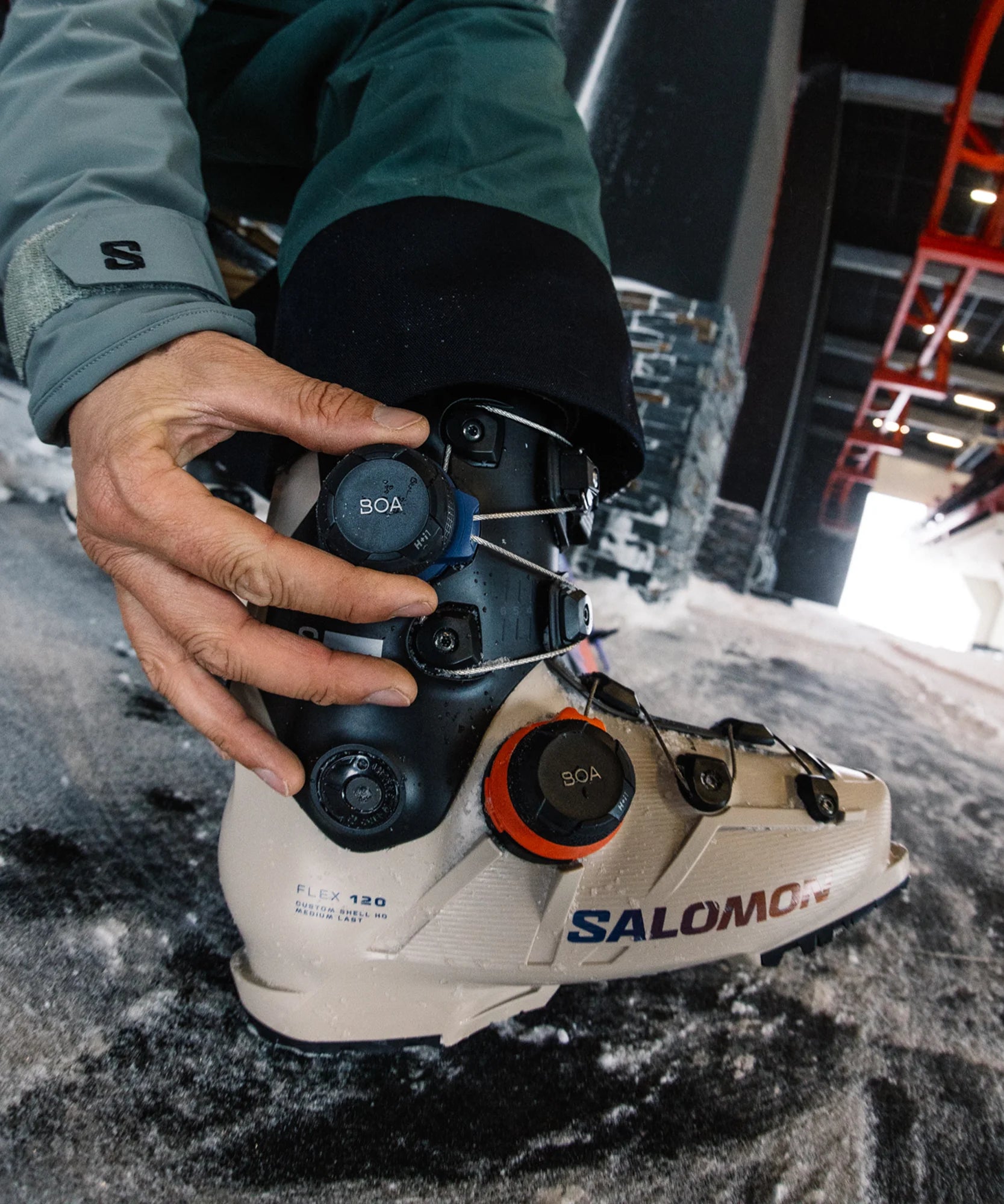 Person adjusting a Salomon ski boot on a snowy surface.