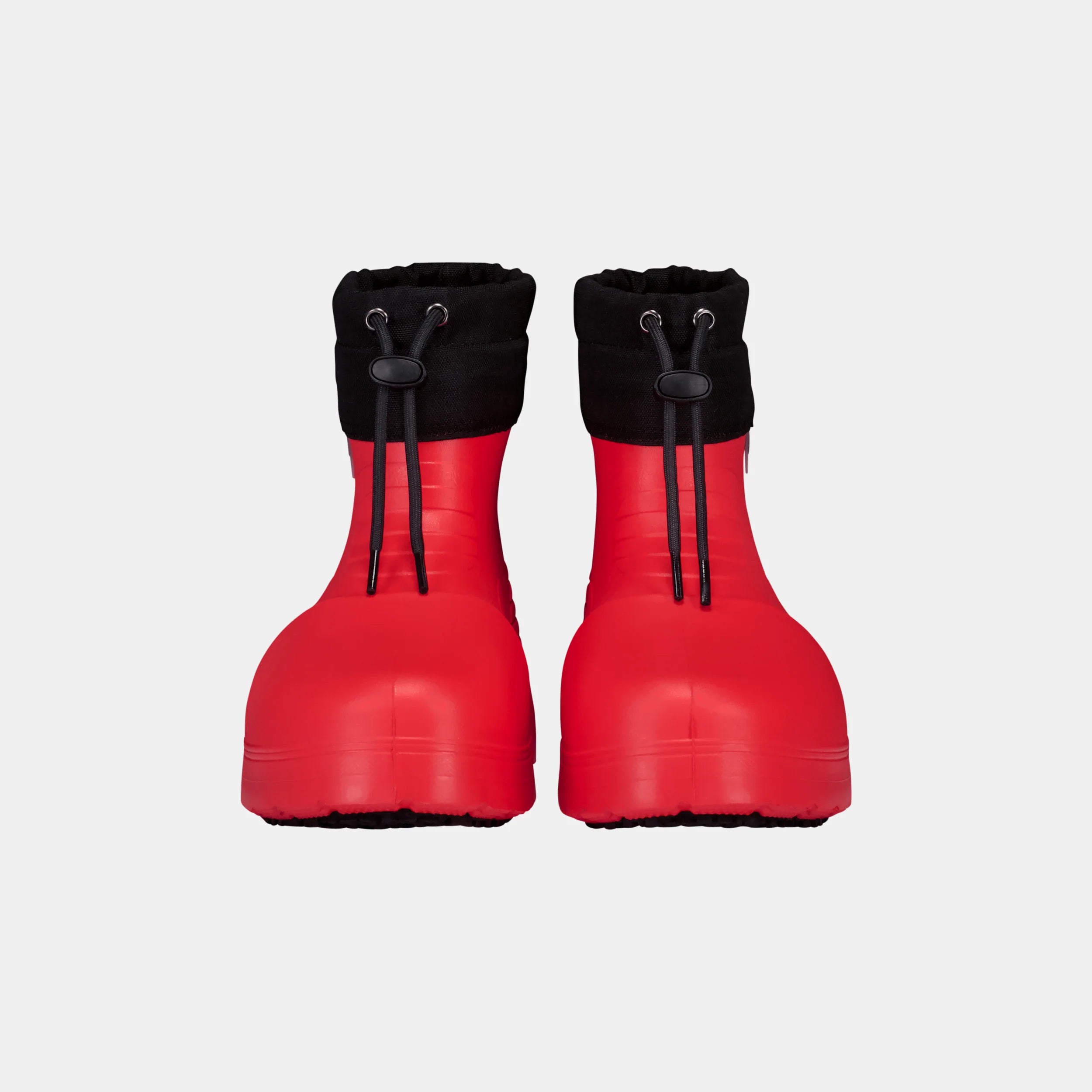 Pair of red rubber boots with black cuffed tops on a light gray background